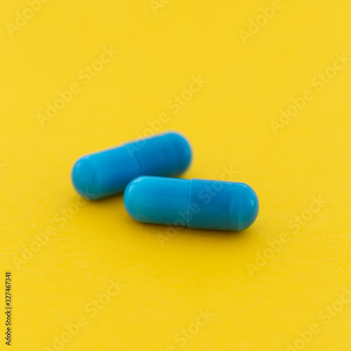 Pharmaceutical medicine blue capsule pills on a yellow background