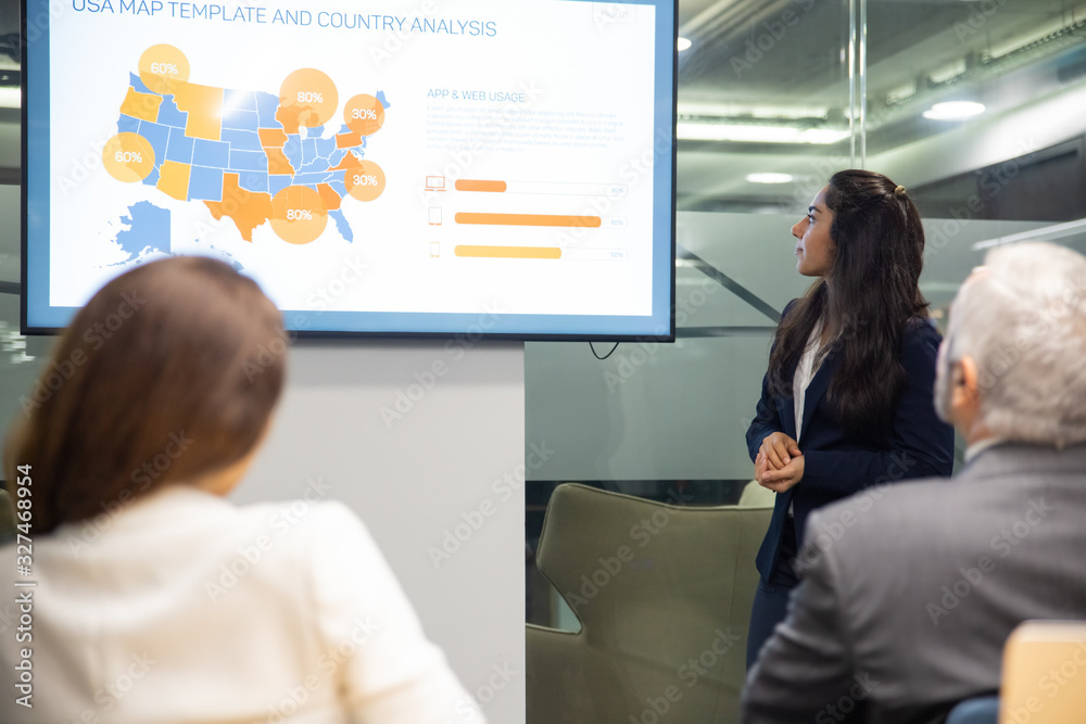 Confident Asian speaker looking at screen with charts. Experienced analyst explaining details of new project for colleagues. Business conference concept Confident Asian speaker looking at screen with charts. Experienced analyst explaining details of new project for colleagues. Business conference concept