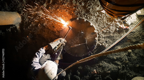 Man doing oxy-acetylene cutting inside confined space with blower ducting and lifeline. 