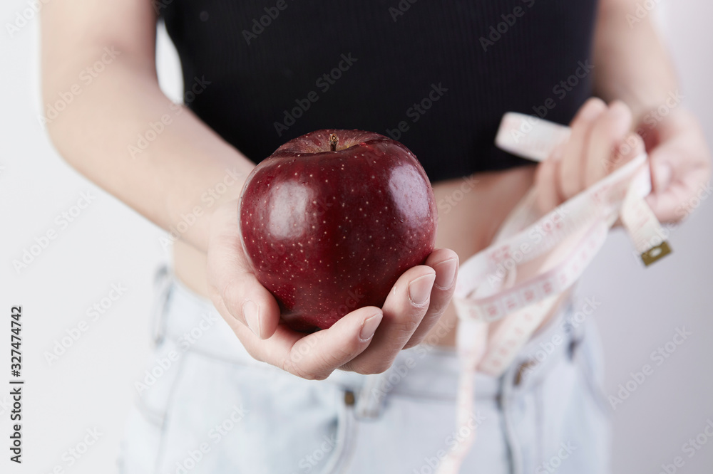 Φωτογραφία A woman with a red apple in one hand and a ruler in the other