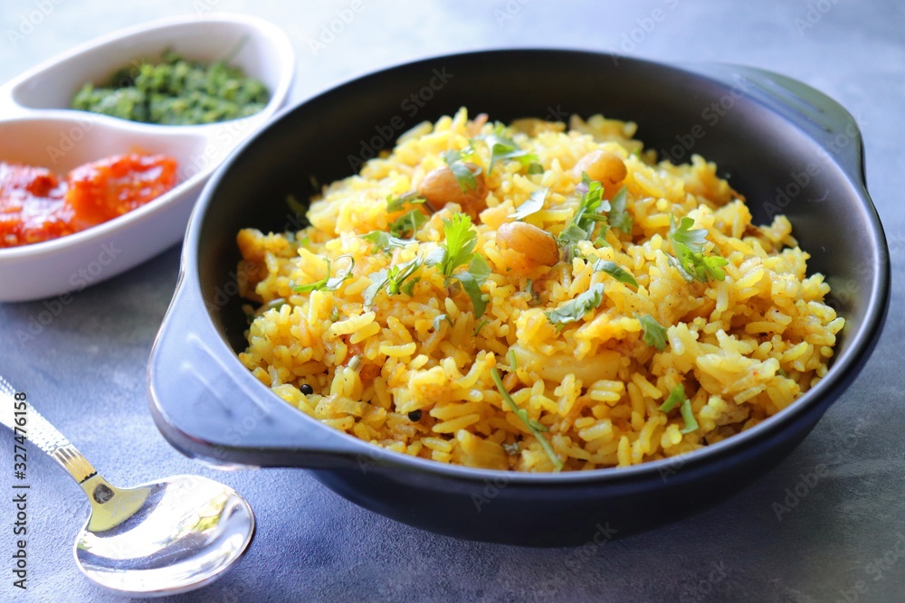 Indian comfort Food - Fresh Masala peanuts rice also known as Peanuts Pulav or rice khichdi. Garnished with coriander. Served hot with green chutney and mango pickle. with Copy space. Indian comfort Food - Fresh Masala peanuts rice also known as Peanuts Pulav or rice khichdi. Garnished with coriander. Served hot with green chutney and mango pickle. with Copy space.