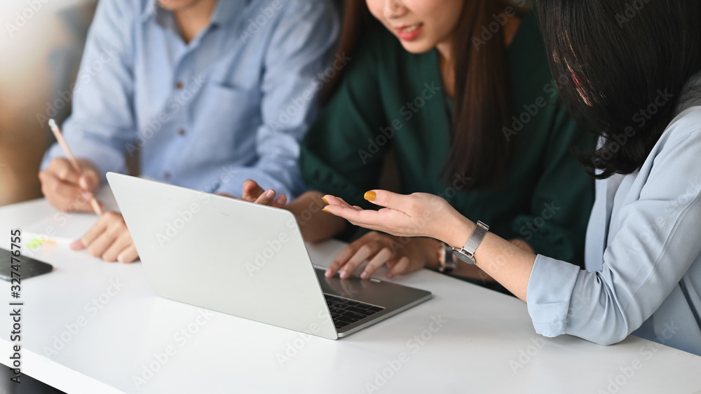 Cropped image of business development team discussing/meeting/working together at the modern meeting table by using a computer laptop and notes. Collaboration concept. Cropped image of business development team discussing/meeting/working together at the modern meeting table by using a computer laptop and notes. Collaboration concept.