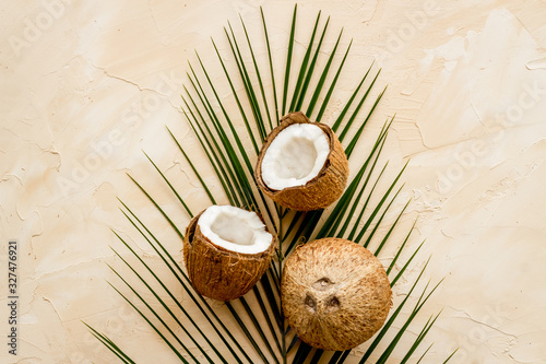 Coconuts and leaves - tropical still life on beige background top-down