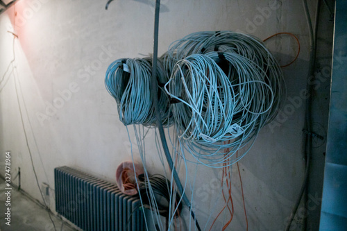 A lot of Internet, Ethernet UTP cables and electrical cables with labels without cable trays are temporary installed on the walls in an apartment of data center during on the construction, overhau