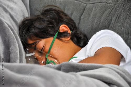coronavirus young boy dead lying mask home sofa blue glove symptom crying thermometer face looking at sanitizer death usa home sick symptoms lying sofa dying sanitizer