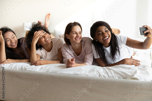 African American girl taking selfie with girlfriends at sleepover party