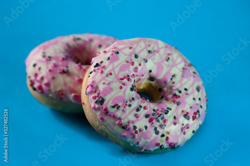 Pink donuts glazed stuffed with strawberry jam, blue background. Close up