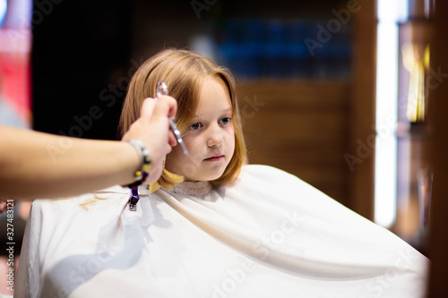 Child getting haircut. Hairdresser cutting hair.