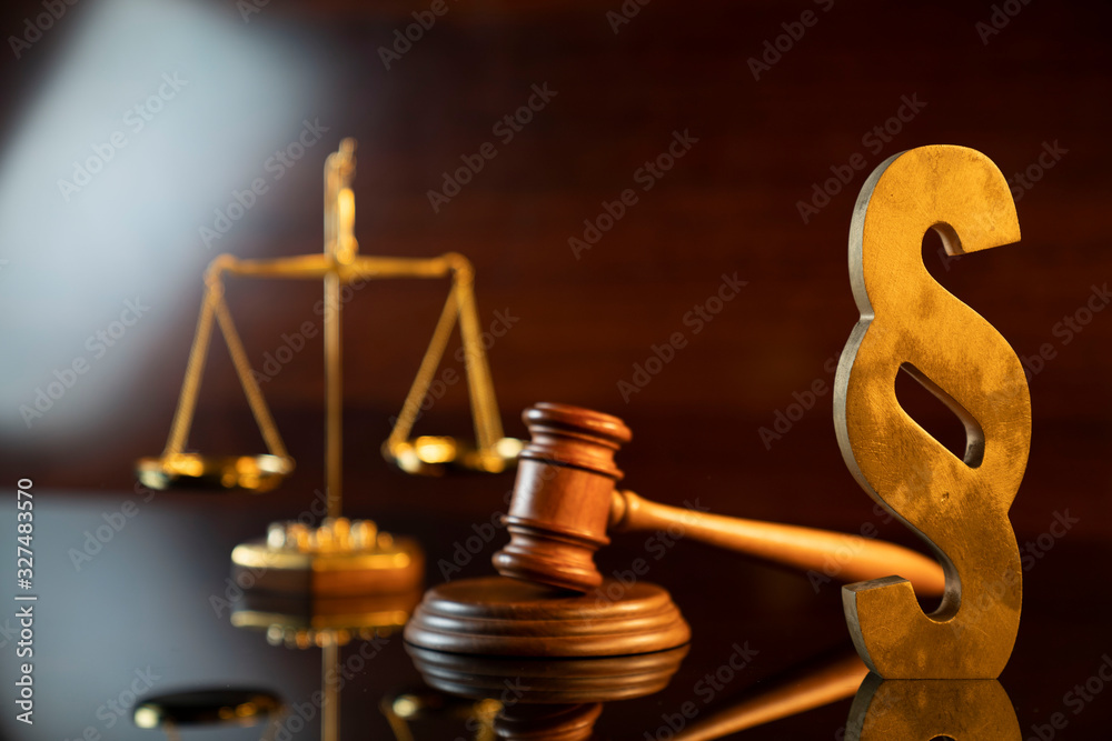 Law and justice concept. Judge’s gavel, scale and paragraph sign on the shining wooden brown table and the brown background. Law and justice concept. Judge’s gavel, scale and paragraph sign on the shining wooden brown table and the brown background.