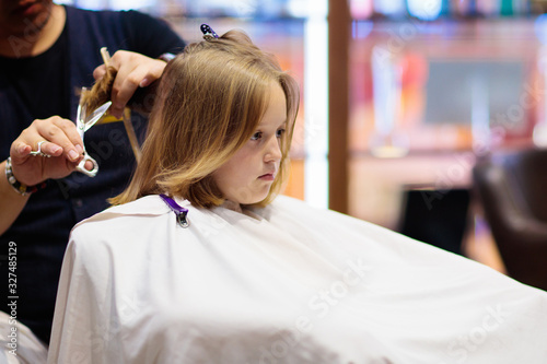 Child getting haircut. Hairdresser cutting hair.