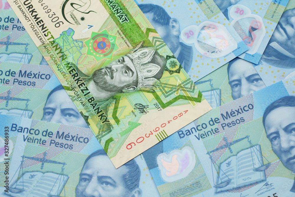 A one manat bank note from Turkmenistan close up in macro with an assortment of Mexican twenty peso bank notes.