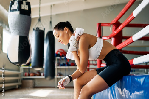 Young beautiful woman relax after fight or workout exercising in boxing ring