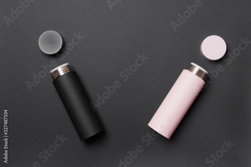 black and pink thermos cup on black colored paper background photo