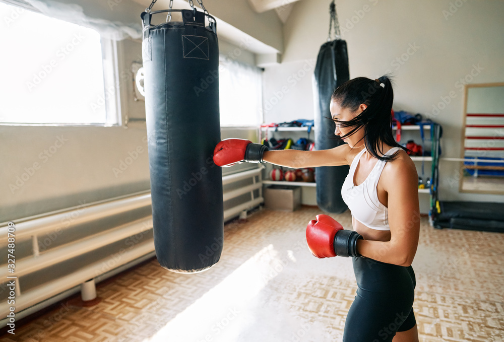 Female boxer hitting a huge punching bag at fitness gym