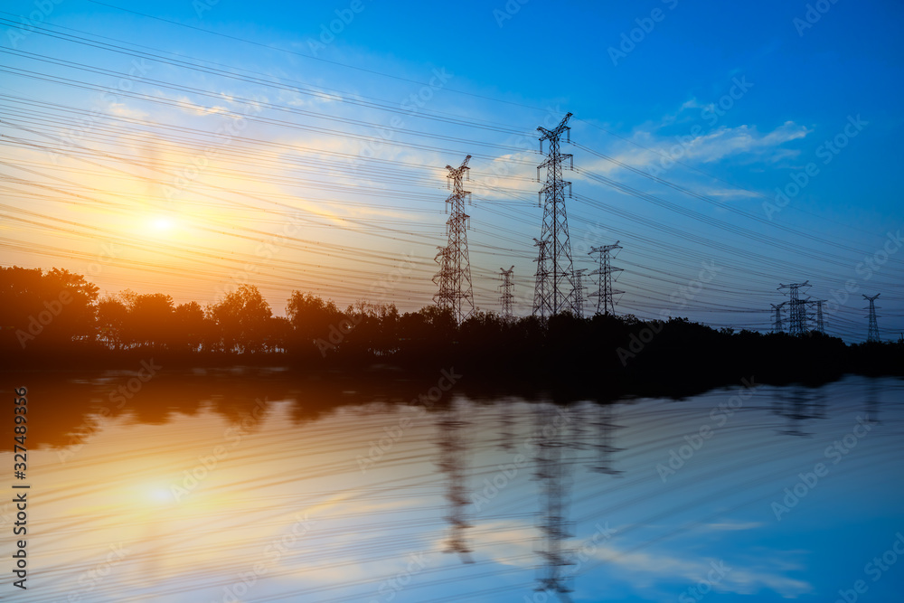 High voltage electrical tower and beautiful river nature landscape at sunset