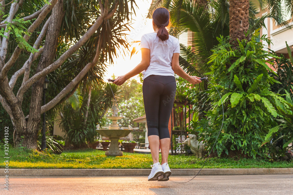 Obraz premium Woman doing exercises with jumping rope at home.