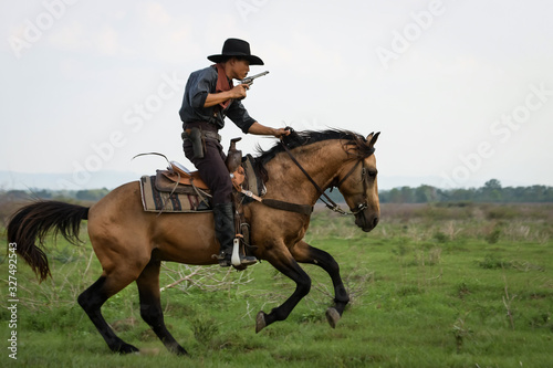 Cowboy man riding horse shooting