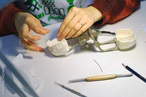 A dentist is working on a cast of a patient's dental jaw to create a prosthetic tooth photo