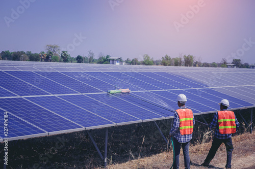 Electrical, instrument technician worker washing and cleaning solar panels at solar electrical system field