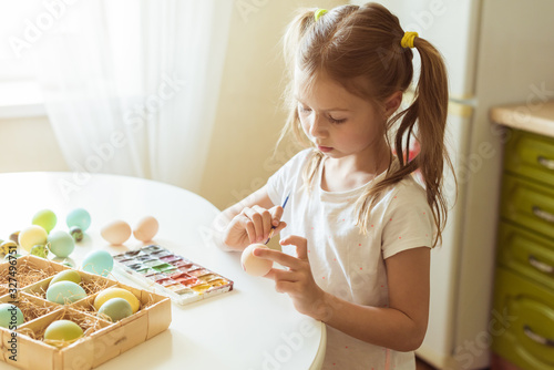 Little girl having fun to paint easter eggs