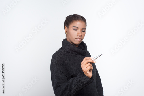 Focused African American woman holding pen. Attractive young lady preparing to write. Writing concept