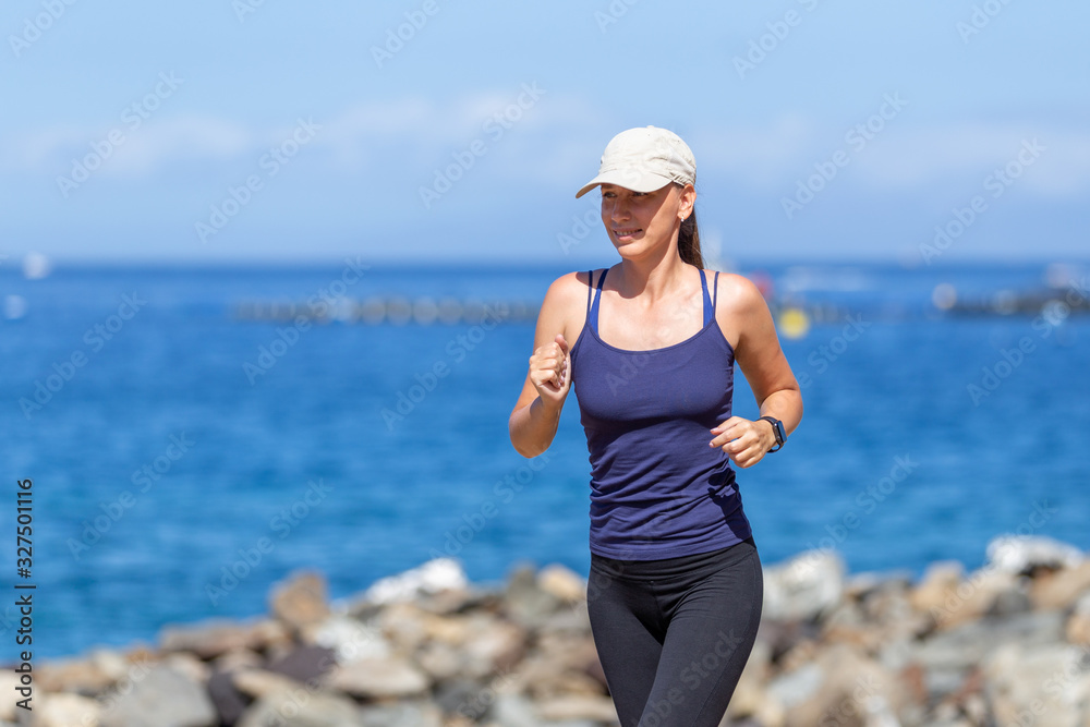 Young slim female runner near the sea jogging in the morning