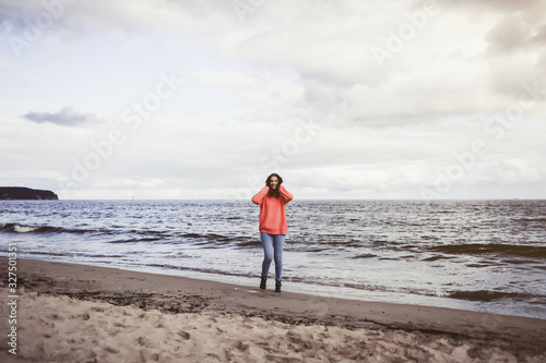 young woman stands on the background of the sea in autumn weather