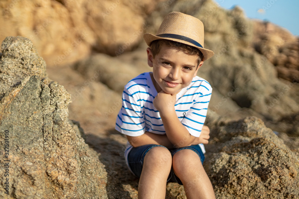 Portrait of a cute child sitting on a rocks near the sea