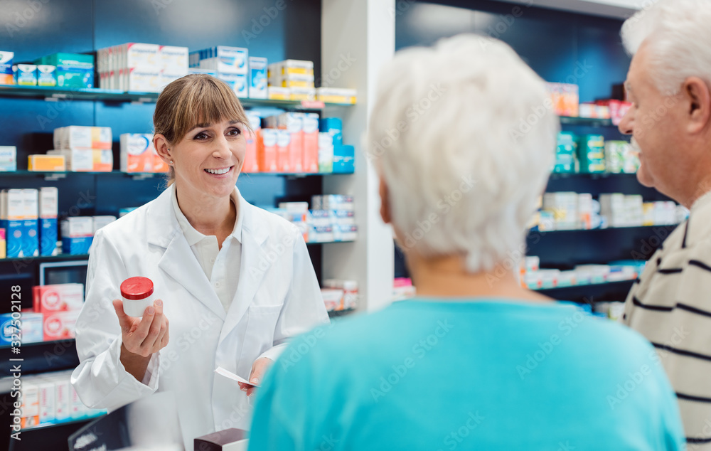 Chemist advising senior couple on a drug in her pharmacy