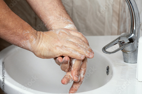 Hands of a man carefully washing his hands closeup.