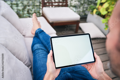 Close up of man lounging on patio and looking at tablet screen