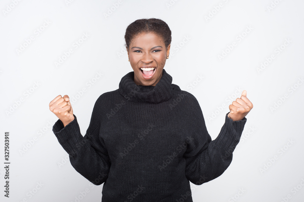 Beautiful African American woman with raised fists. Successful young lady looking at camera. Success concept