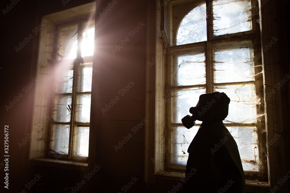 Dramatic portrait of a woman wearing a gas mask in a ruined building.