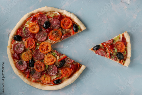 Foto Pizza with a cut out piece on a light blue background, Closeup