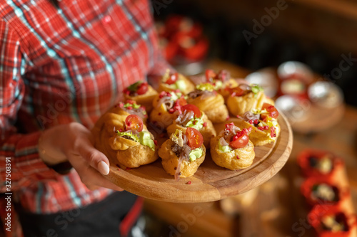 Profiteroles with pate, decorated with green salad, tomato and onion, on a tray.