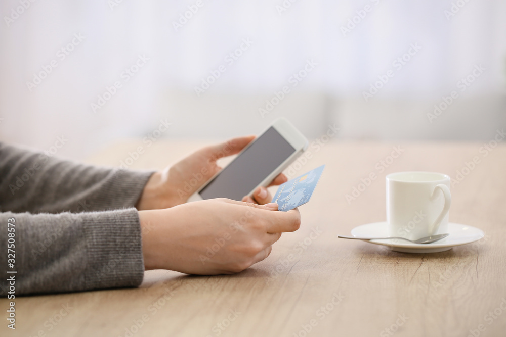 Woman using mobile phone for online banking at table