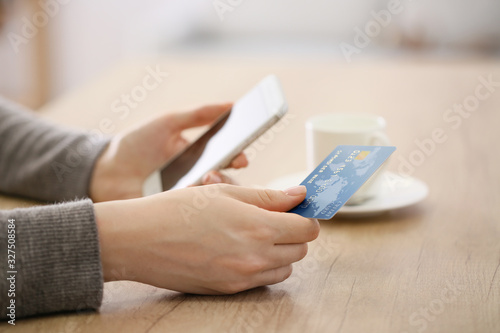Woman using mobile phone for online banking at table © Pixel-Shot