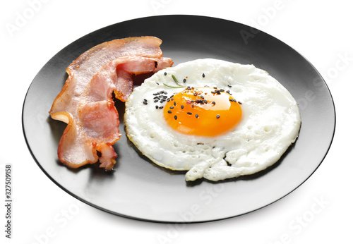 Plate with fried egg and bacon on white background