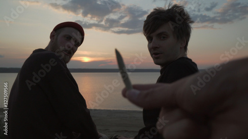 Φωτογραφία Hand from first person view offering smoking joint with weed to two males