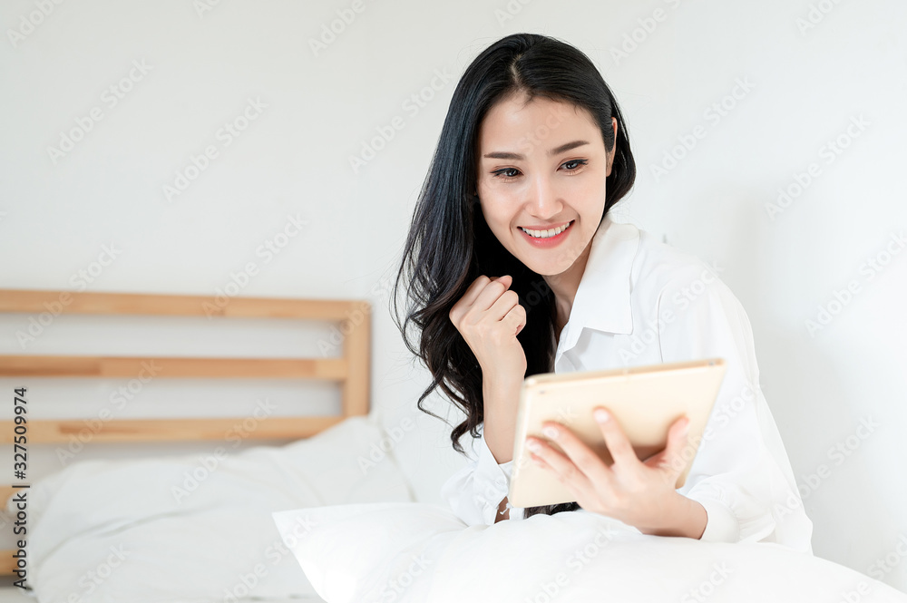 Asian women are happy with what was on her tablet. Success achievement, happy life, positive thinking, health, life planning and vacation concept.