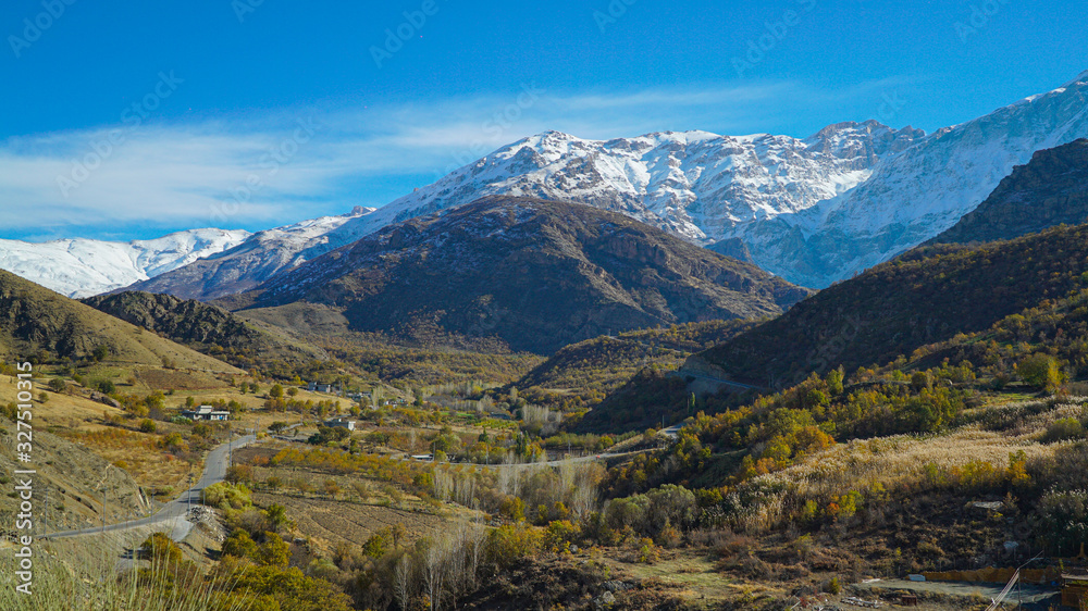 a view of mountains covered with snow in the fall season in  the north of Iraq Kurdistan Region with green landscape and trees in the foreground