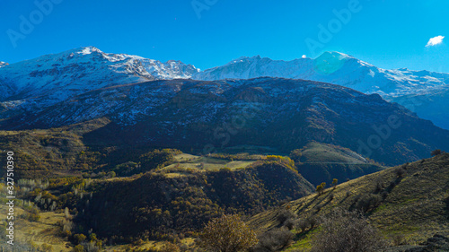 a view of mountains covered with snow in the fall season in  the north of Iraq Kurdistan Region with green landscape and trees in the foreground © Darbaz