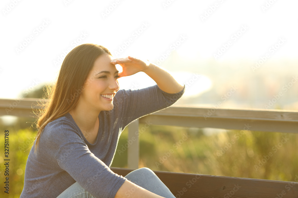 Happy woman looking away with hand on her forehead