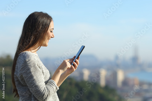 Happy woman looking at her phone with coast background