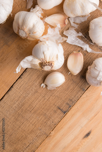 A lot of garlic on a wooden background  top view. Background for design. Vertical photo with space