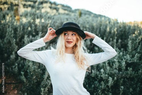 Chica felíz rubia con sombrero con fondo natural verde.
