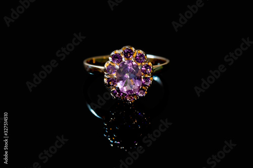 Beautiful golden ring with purple gemstone isolated on black background