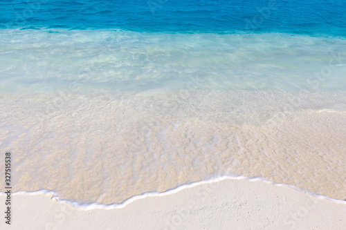 White sandy beach and crystal-blue ocean wave.