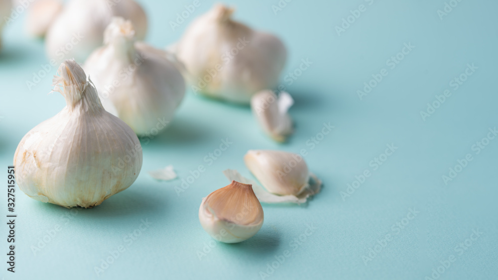 A lot of garlic on a light blue background. Close up, horizontal photo with space