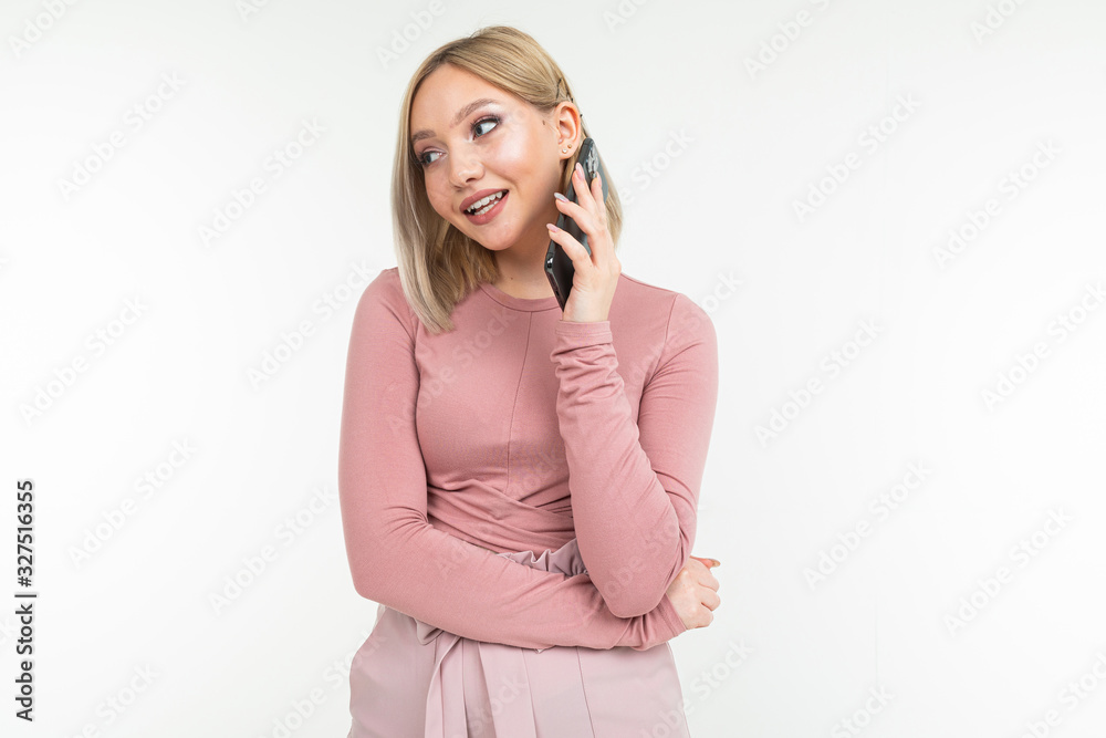 smiling girl in pink clothes communicates on the phone on a white background smiling girl in pink clothes communicates on the phone on a white background